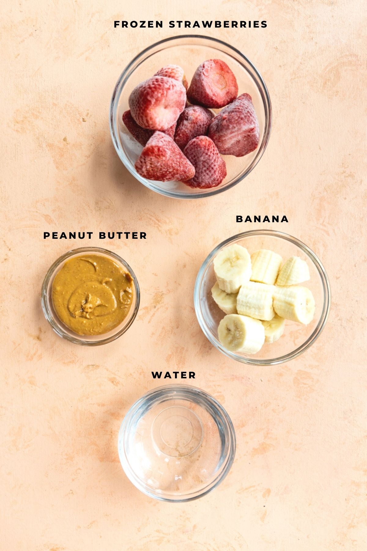 Ingredients for peanut butter strawberry smoothie measured out into small cups.