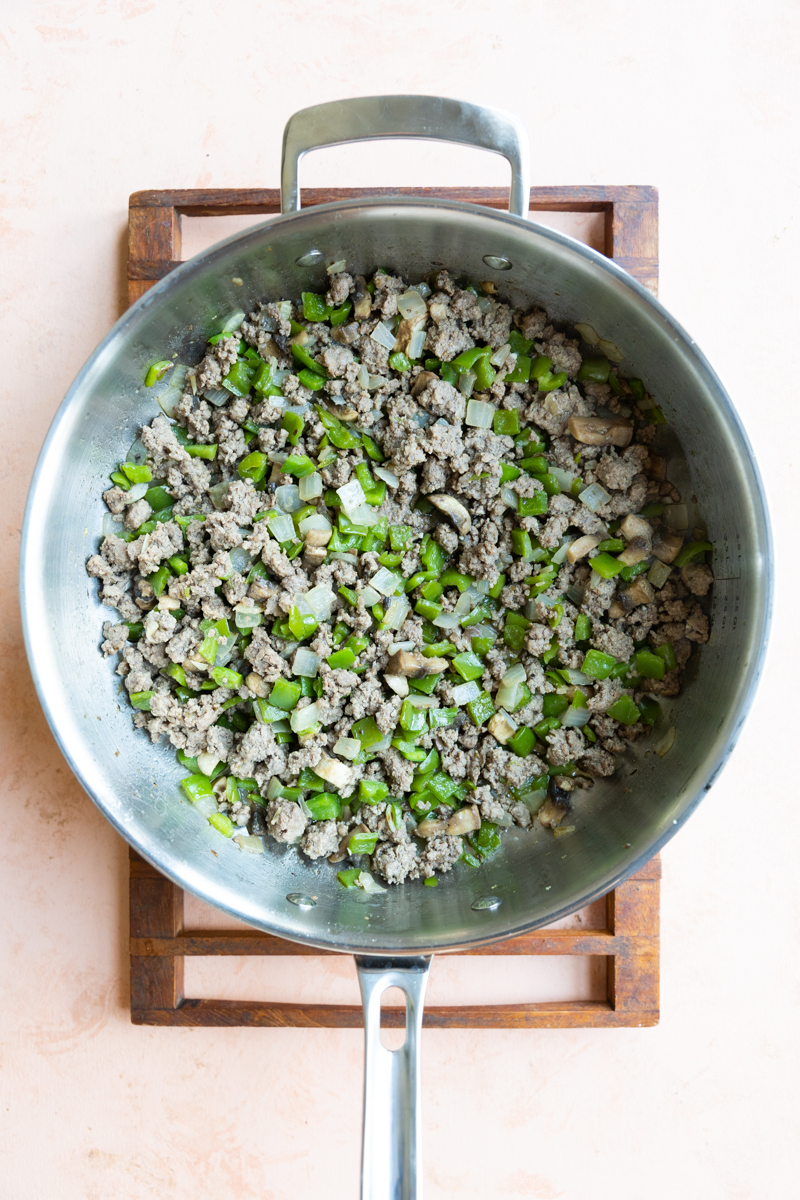 Ground beef, onions, and bell peppers in saute pan.