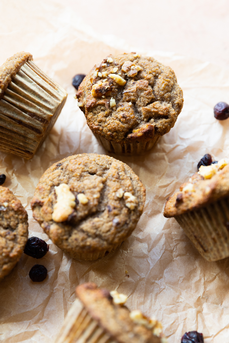 Gluten Free Cranberry Walnut Muffins scattered on parchment paper.