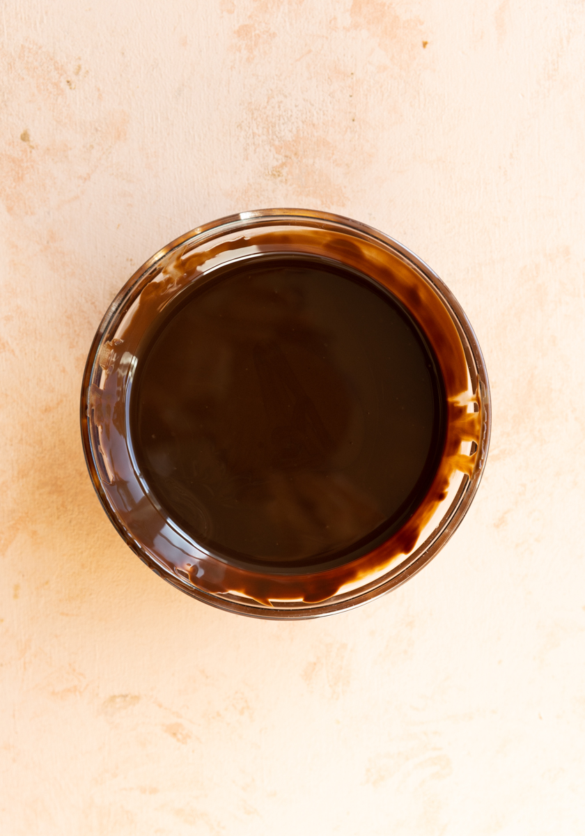 Melted dark chocolate in a glass bowl.