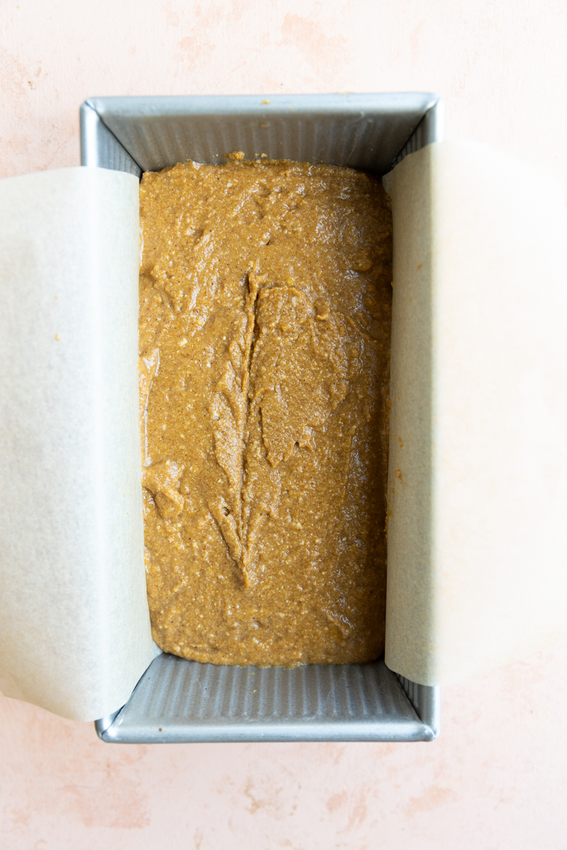 Pumpkin bread batter in baking pan with parchment paper.