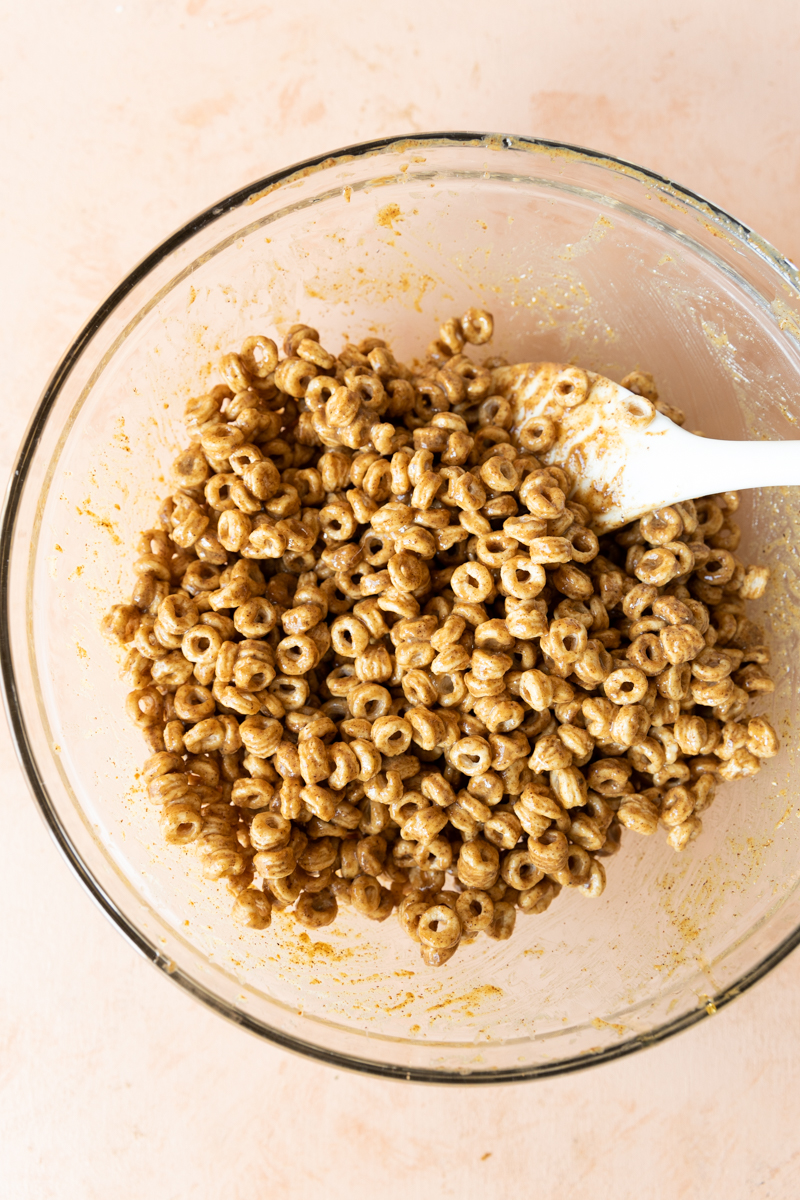 Cereal mixed with almond butter, coconut oil, honey, and cinnamon in a bowl.
