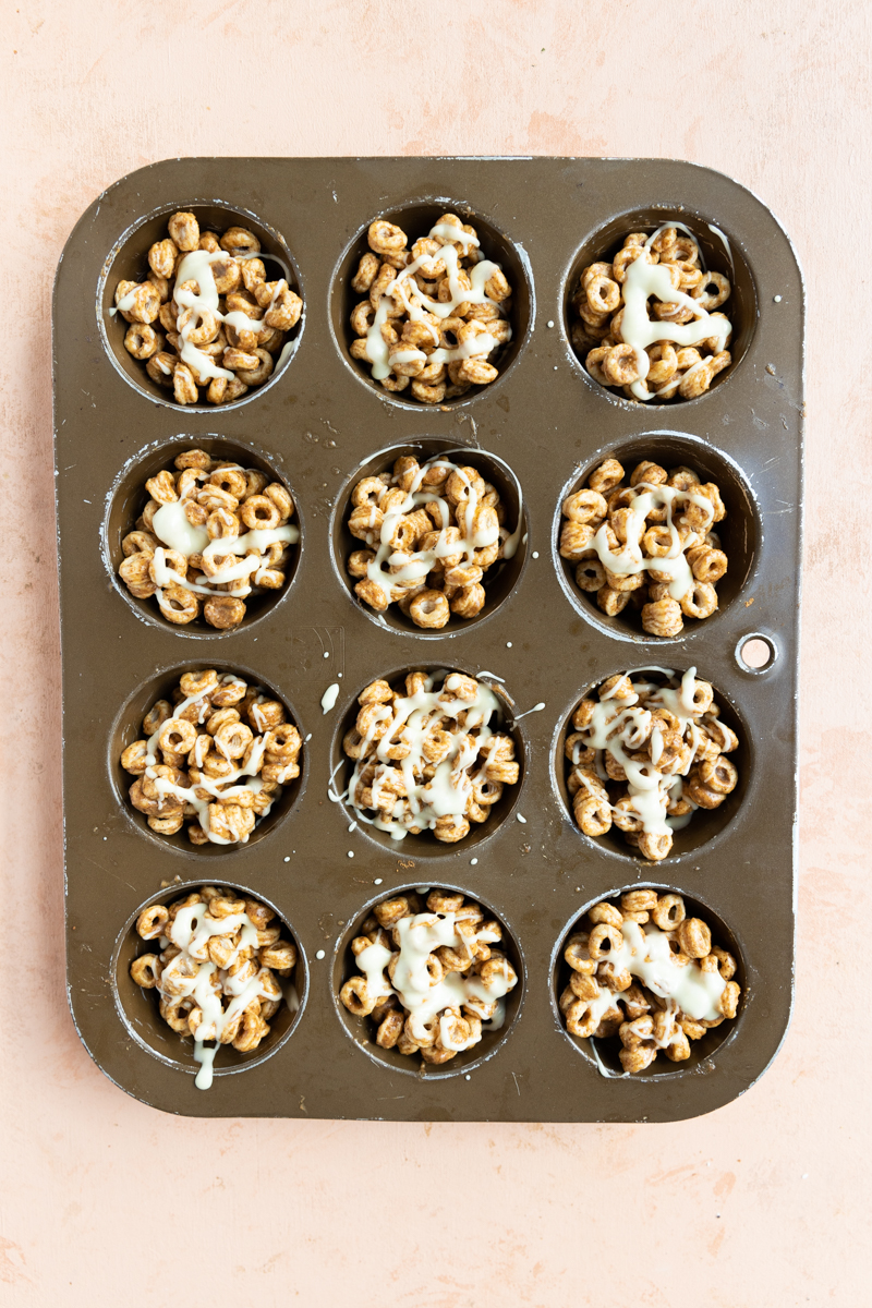 Cereal cookies in muffin tin with white chocolate drizzle on top.