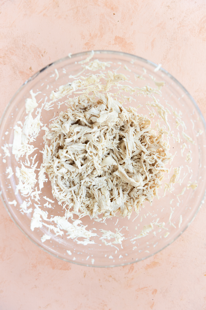 Shredded chicken in glass bowl.