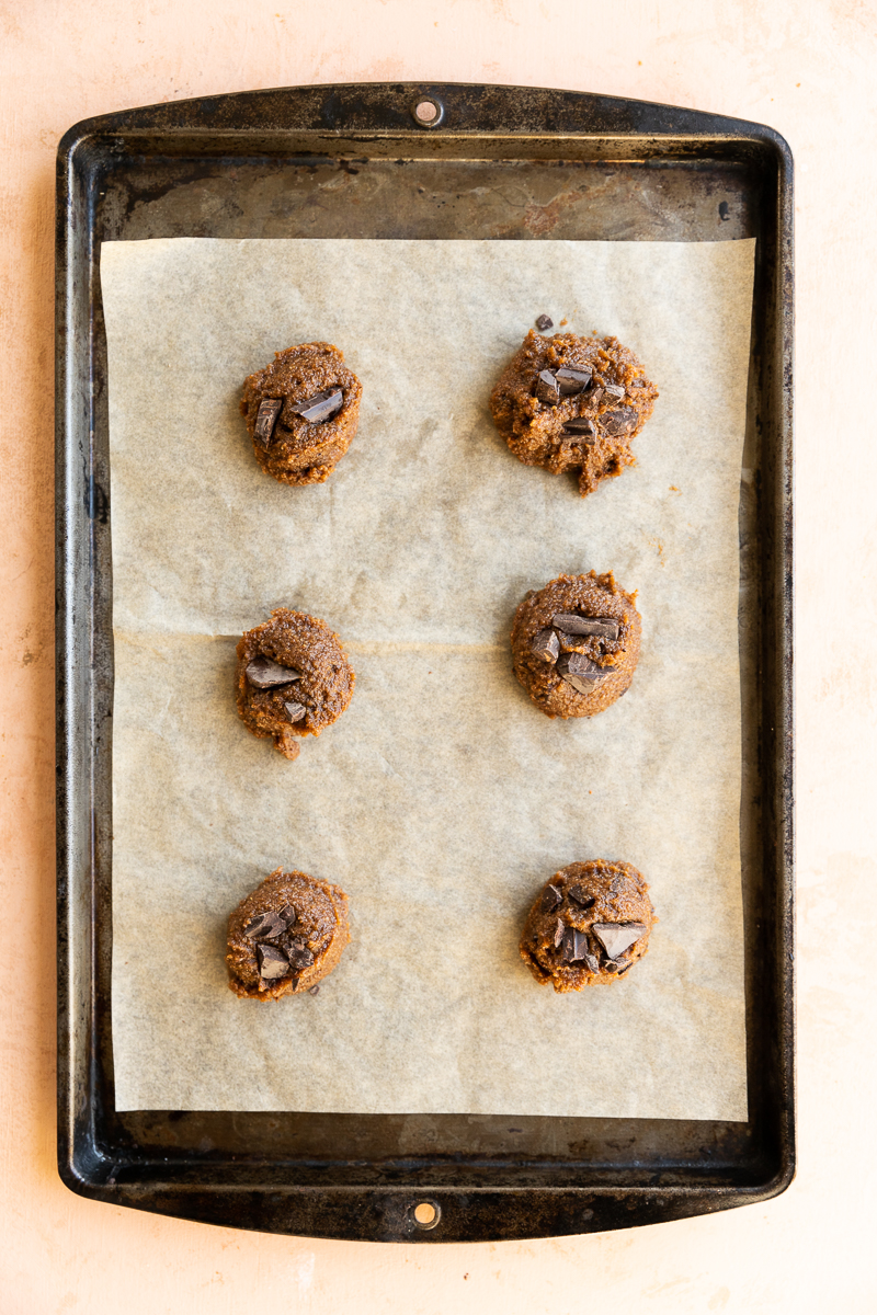 Cookies with chocolate chunks on parchment paper lined baking sheet.