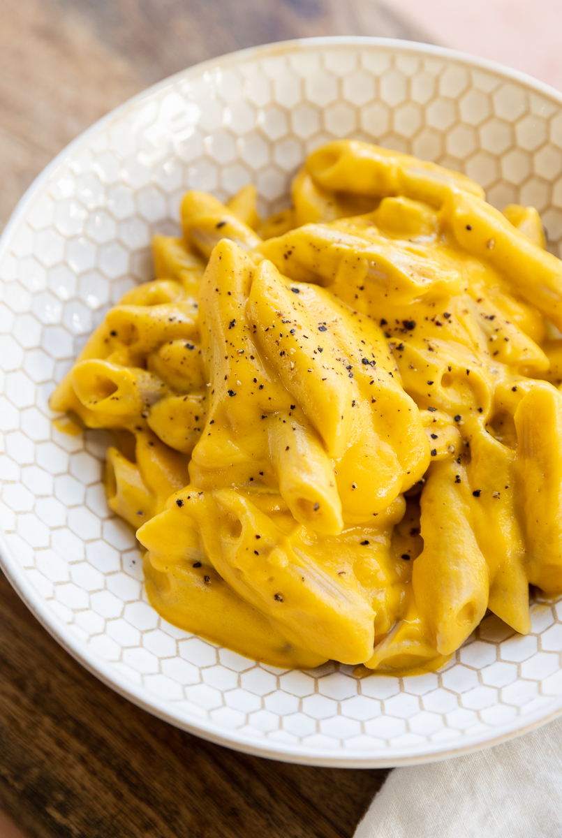 Close up picture of penne in a bowl with vegan butternut squash sauce.