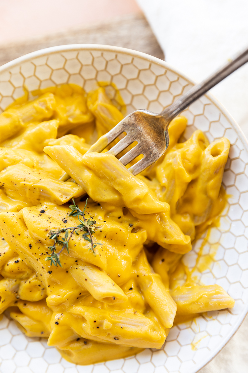 Bowl of creamy butternut squash pasta with fork scooping up penne.