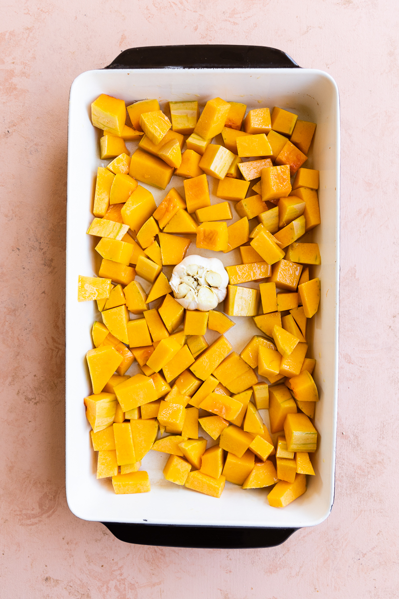 Butternut squash and garlic in a baking dish.