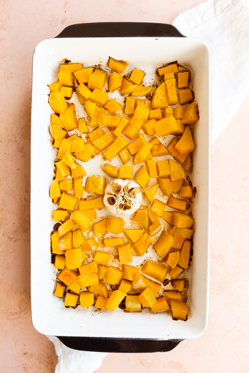 Baked butternut squash with roasted garlic in a baking pan.