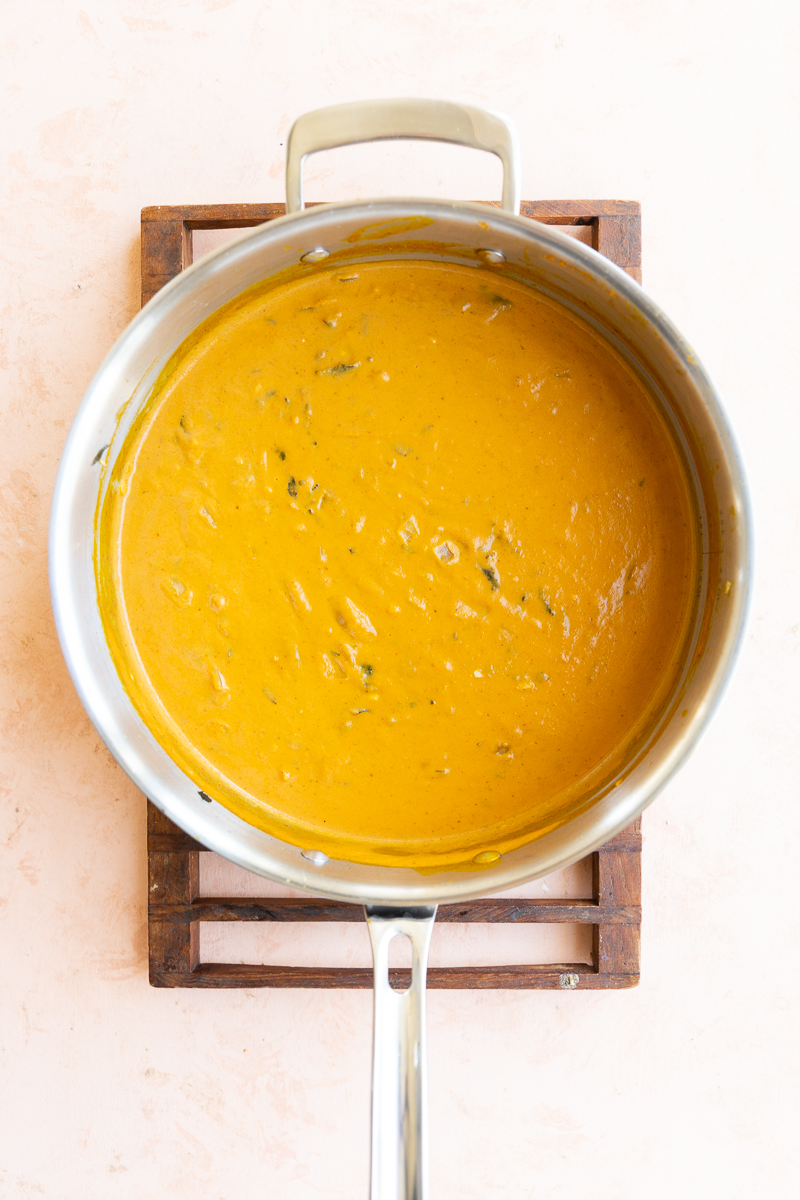 Pumpkin pasta sauce cooking in large pan.