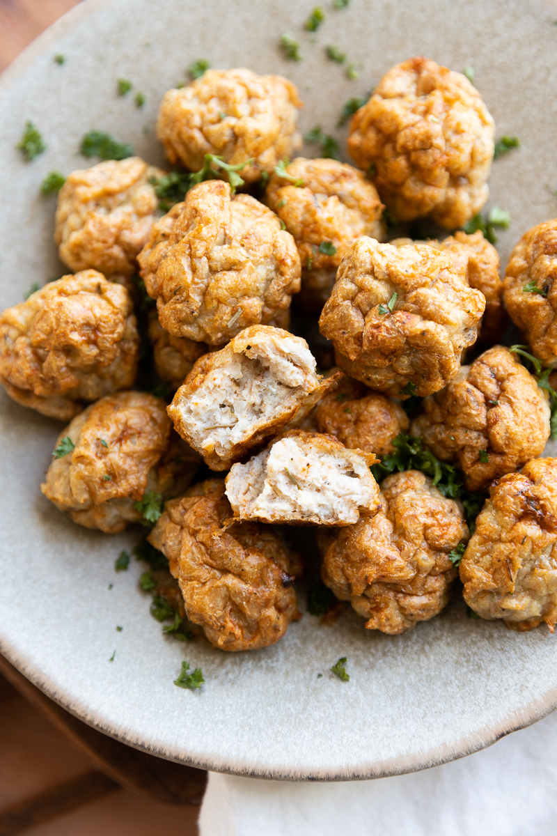 Chicken meatballs on a plate with one cut in half.