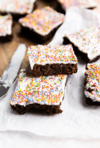 Gingerbread bars with white frosting stacked on top of each other.