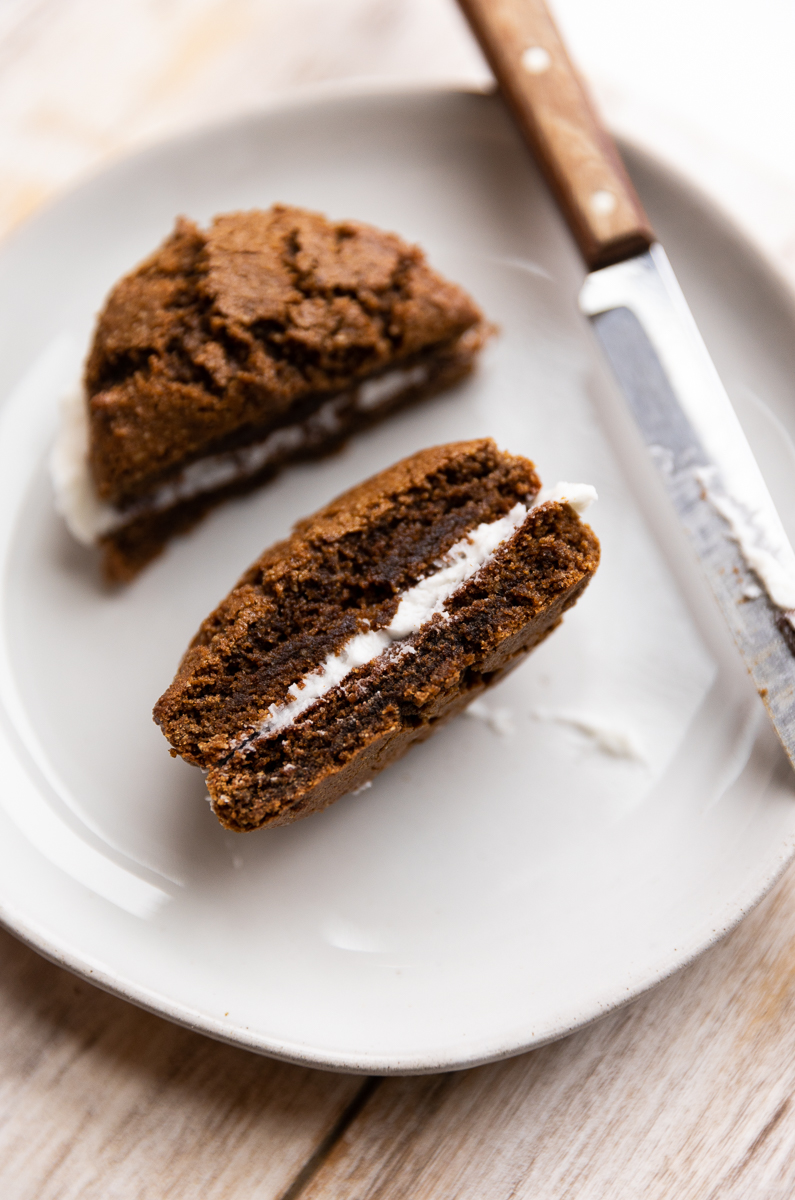Gingerbread cookie sandwich cut in half on a small plate.