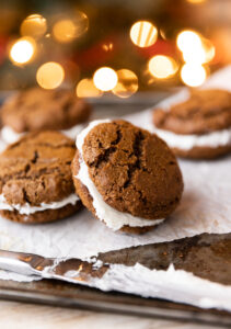Gingerbread cookie sandwiches with christmas lights in the background.