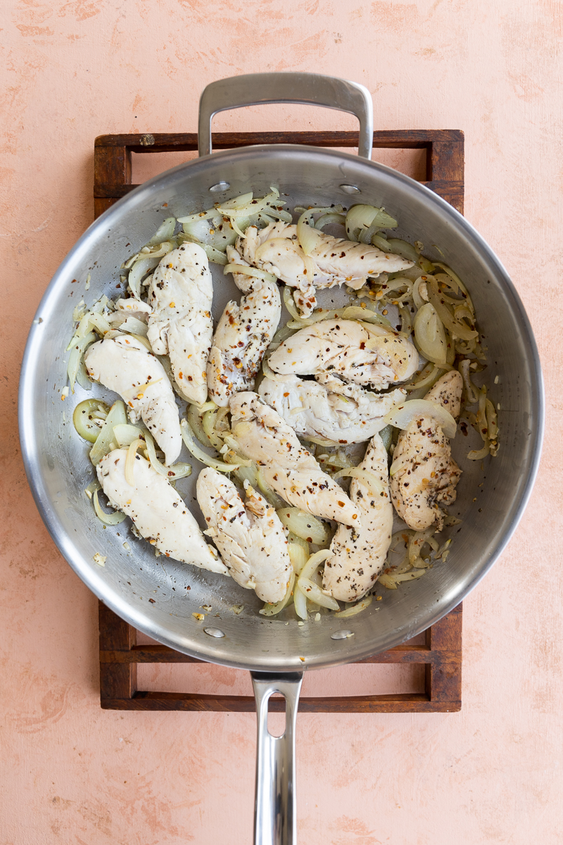 Chicken tenders cooking with onions and garlic.