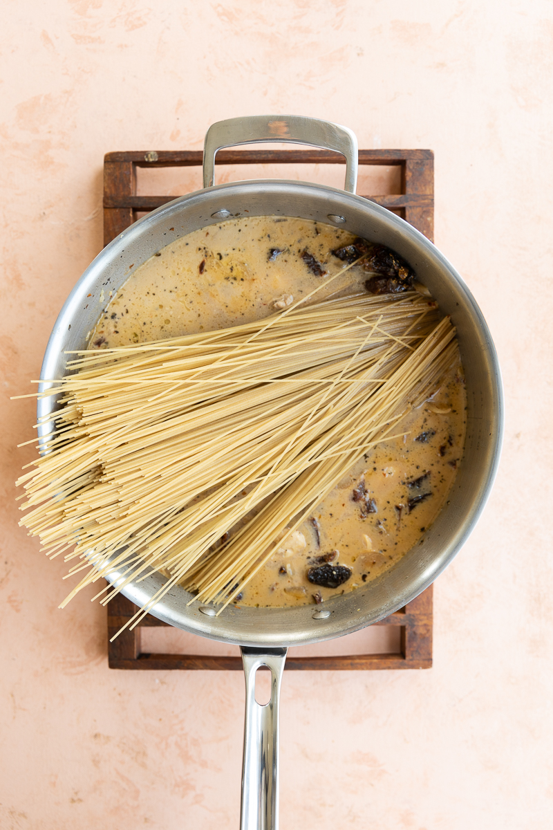 Uncooked pasta in chicken and broth mixture.