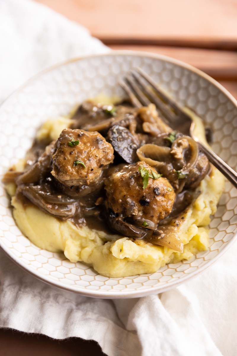 Meatballs in a bowl with mashed potatoes.
