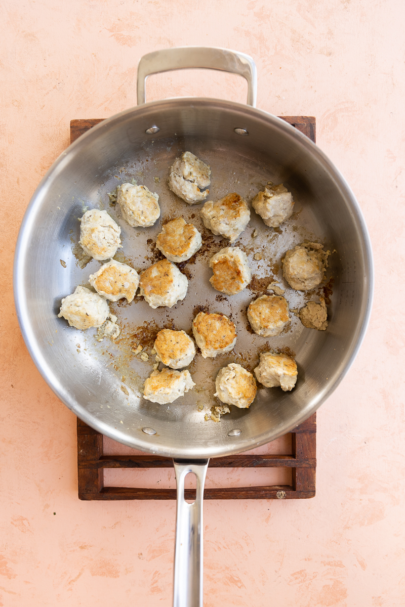 Cooked chicken meatballs in pan.