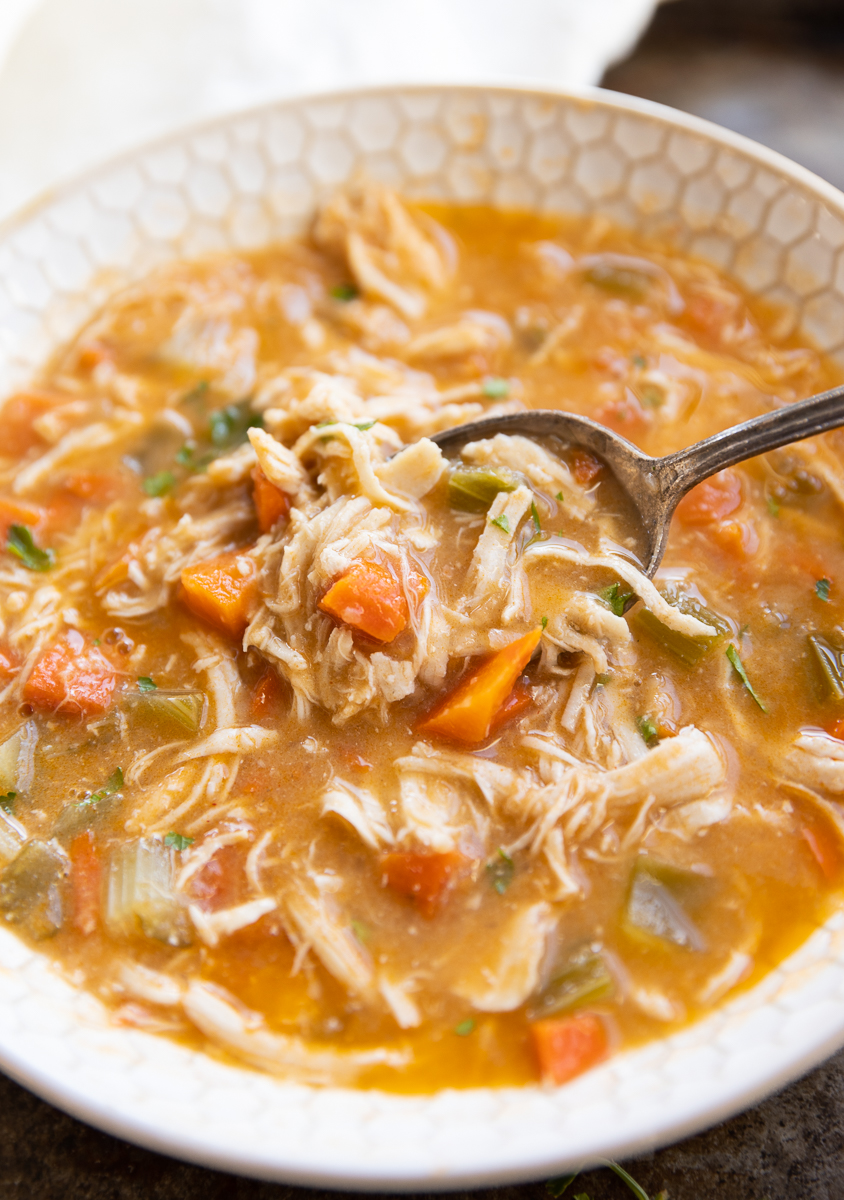Spoon scooping out spicy chicken soup.