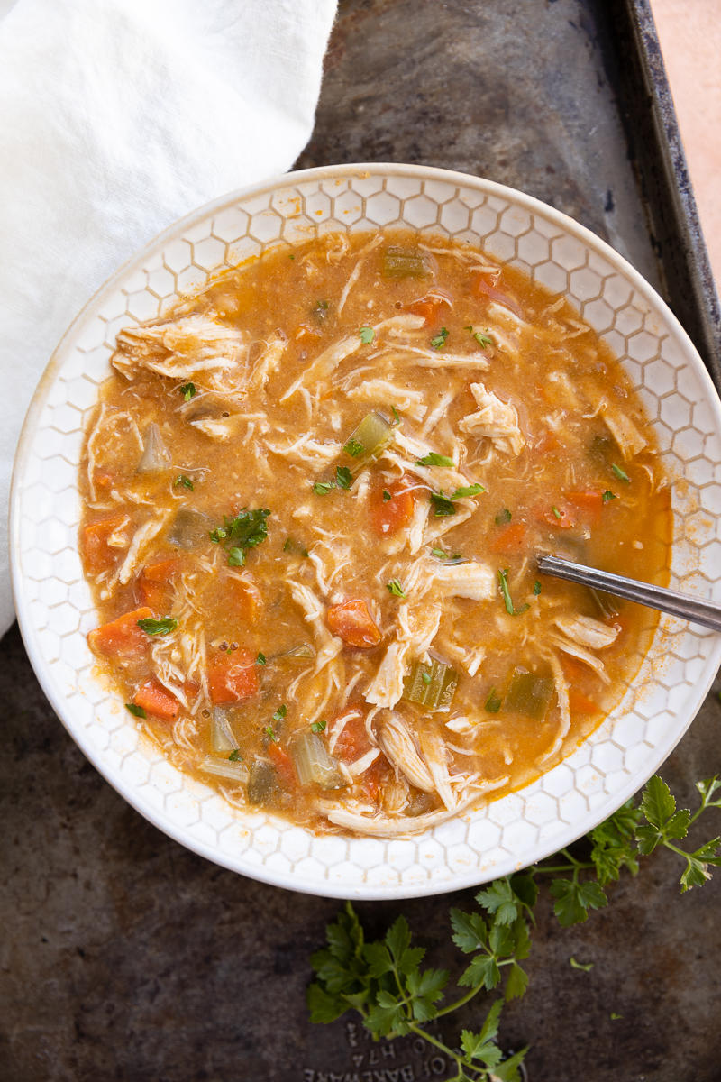 Spicy chicken soup in a white bowl on a black background.