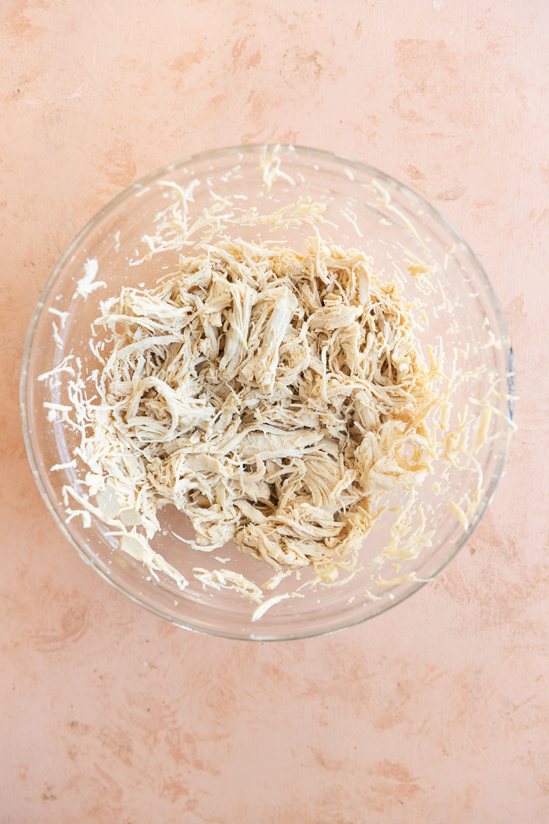 Shredded chicken in glass bowl.