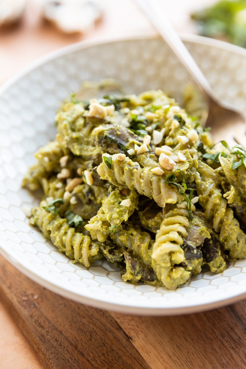 Close up of ceramic bowl filled with pesto pasta.