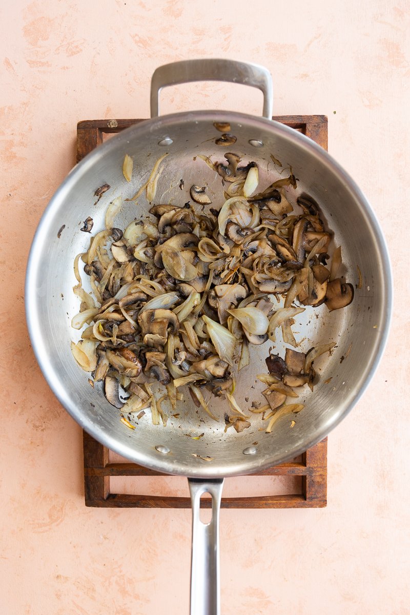 Cooked mushrooms and onions in a pan.