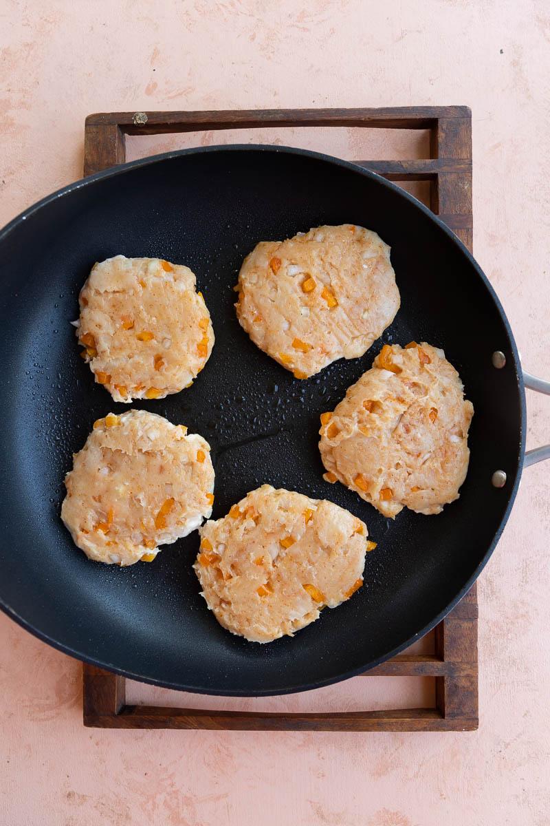 Chicken burgers on skillet.