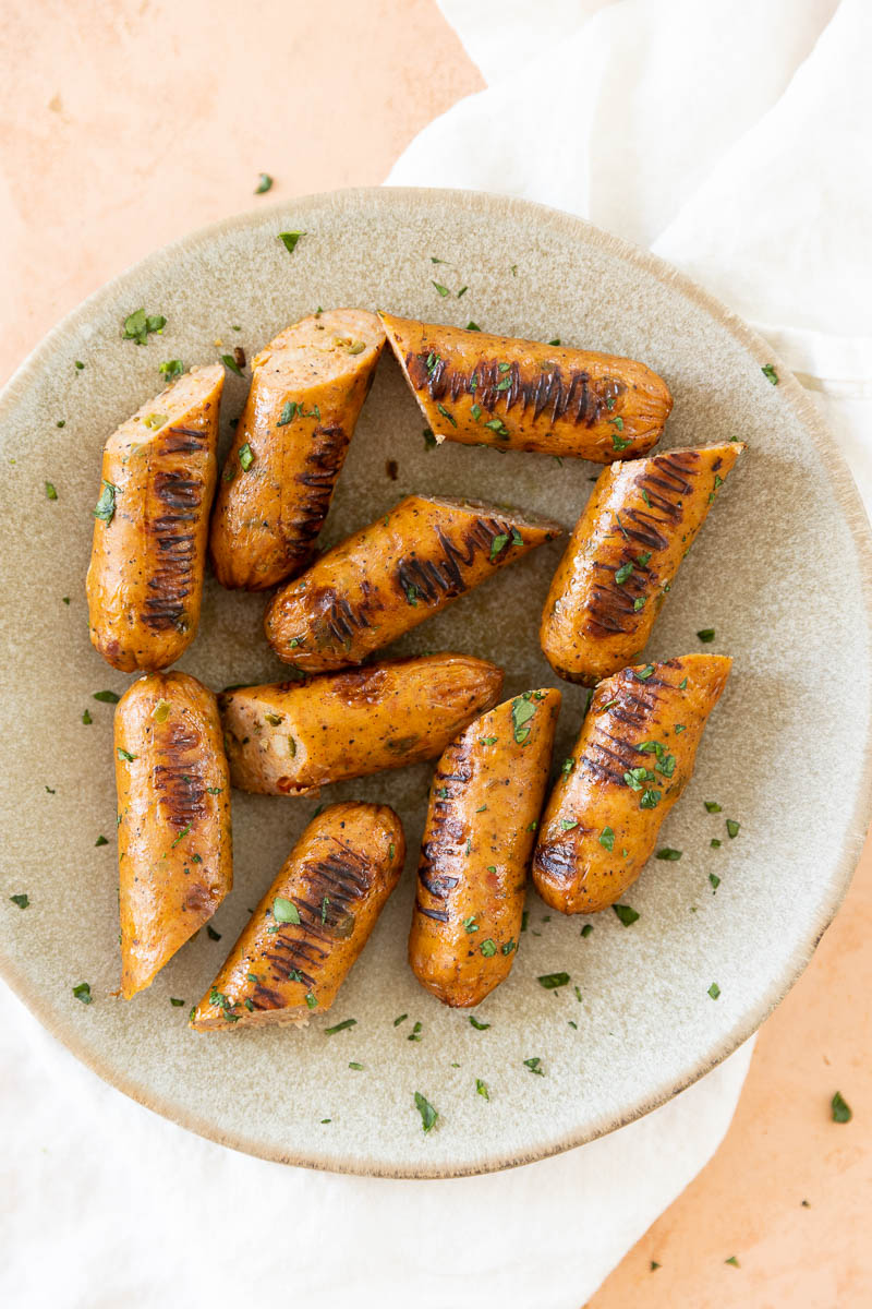Chicken sausages cut in half on a ceramic plate.