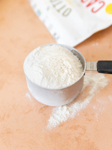 Cassava flour spilling out of measuring cup.
