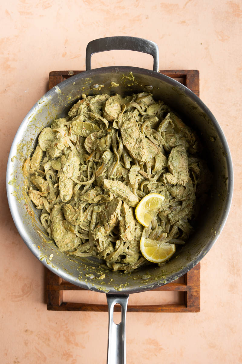 Artichoke pesto chicken pasta in stainless steel pan.