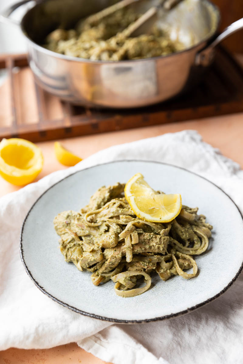 Finished pasta plated with cooking pan in background.