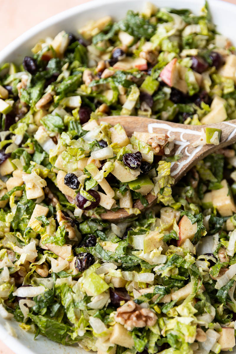 Wooden spoon scooping fruit and nut salad.
