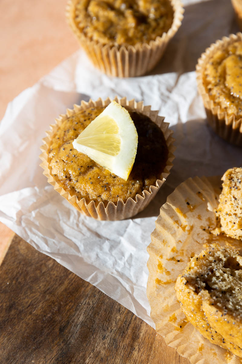 Close up picture of lemon poppyseed cupcake with lemon wedge on top.