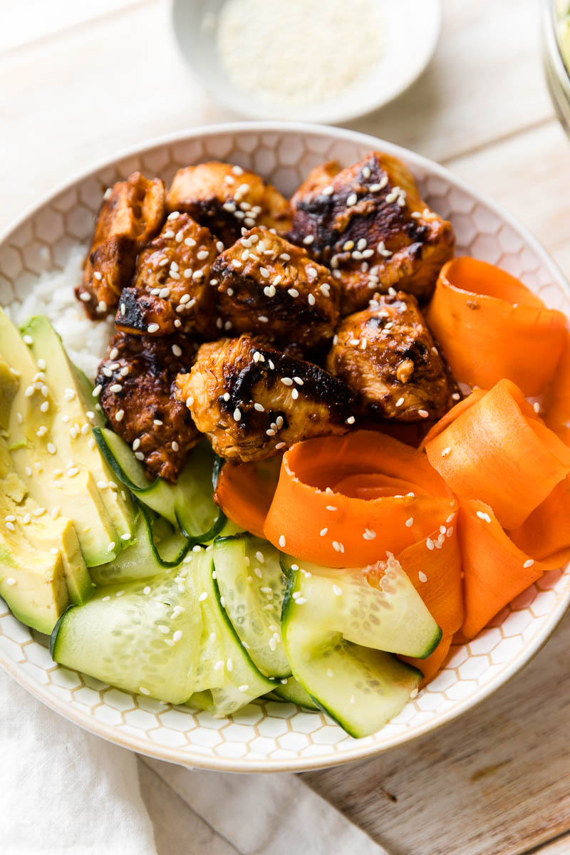 Close up picture of BBQ chicken bowl with thinly sliced carrots and cucumber.