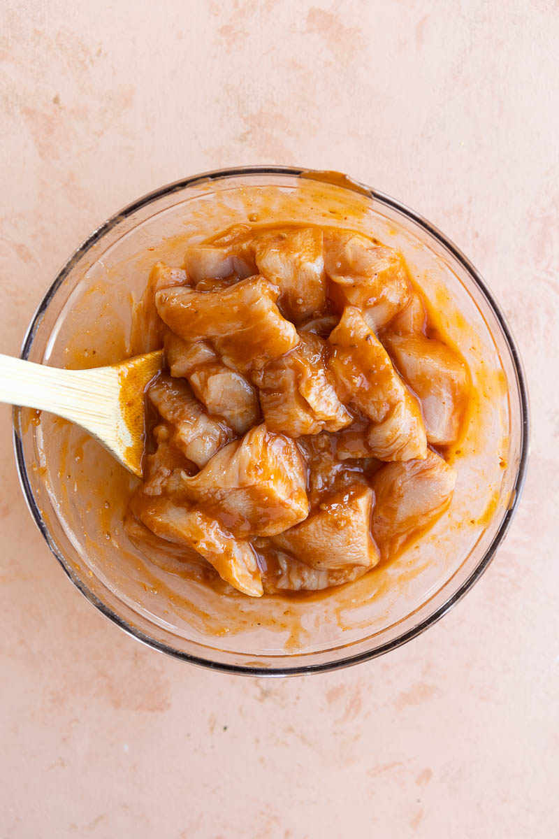 Chicken marinating in glass bowl.