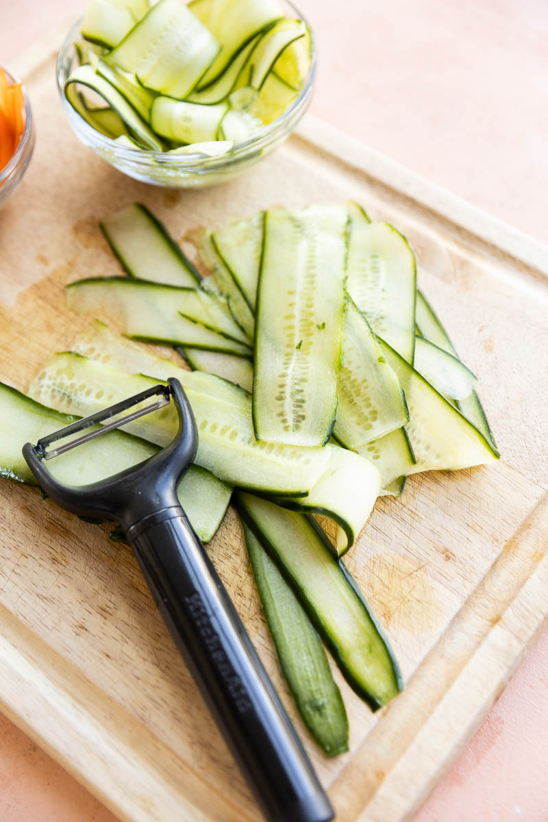 Thinly sliced cucumber on a cutting board.