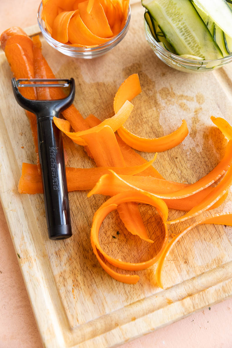Thinly sliced carrots on a cutting board.