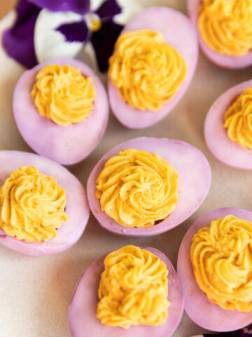 Pink deviled eggs on a plate with flowers.