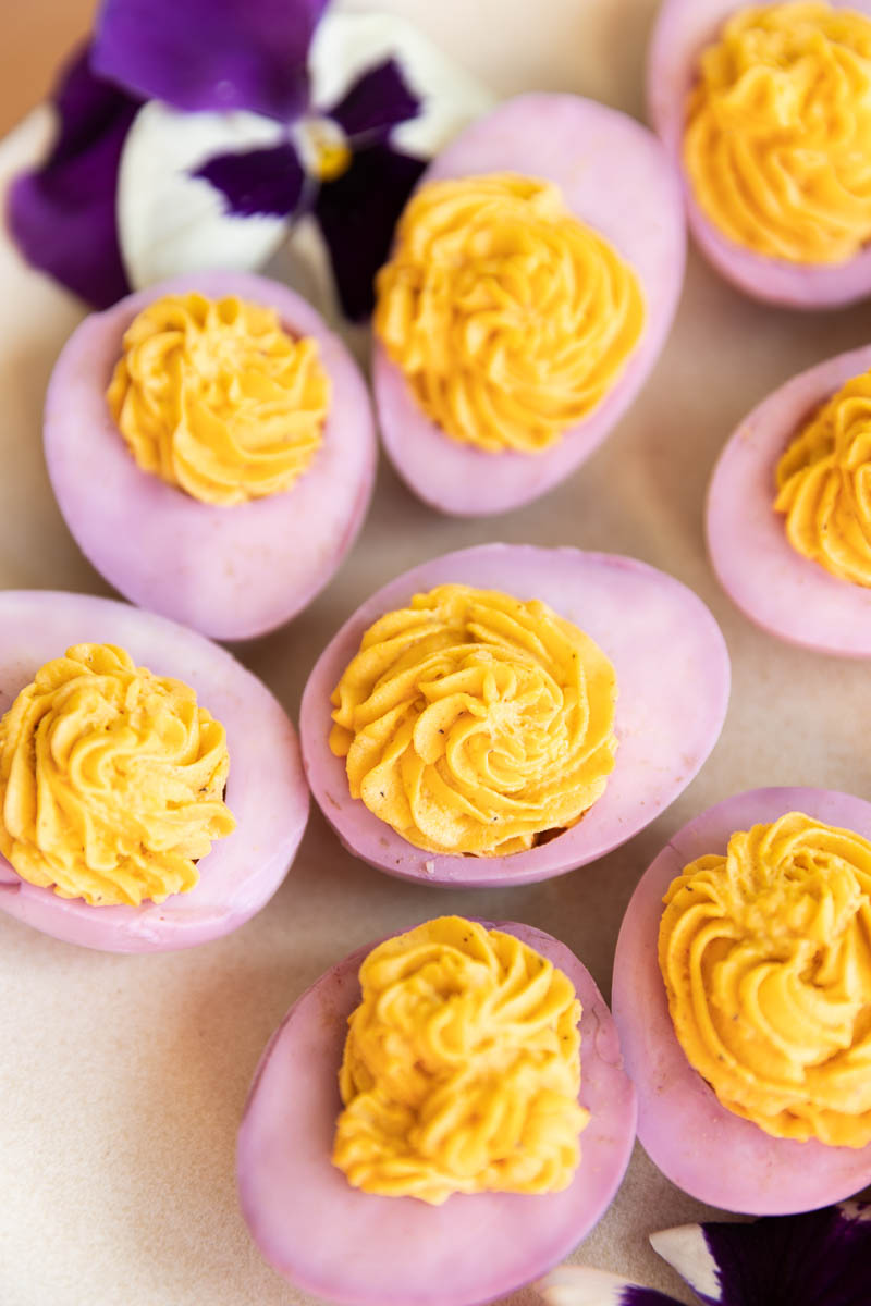 Pink deviled eggs on a plate with flowers.