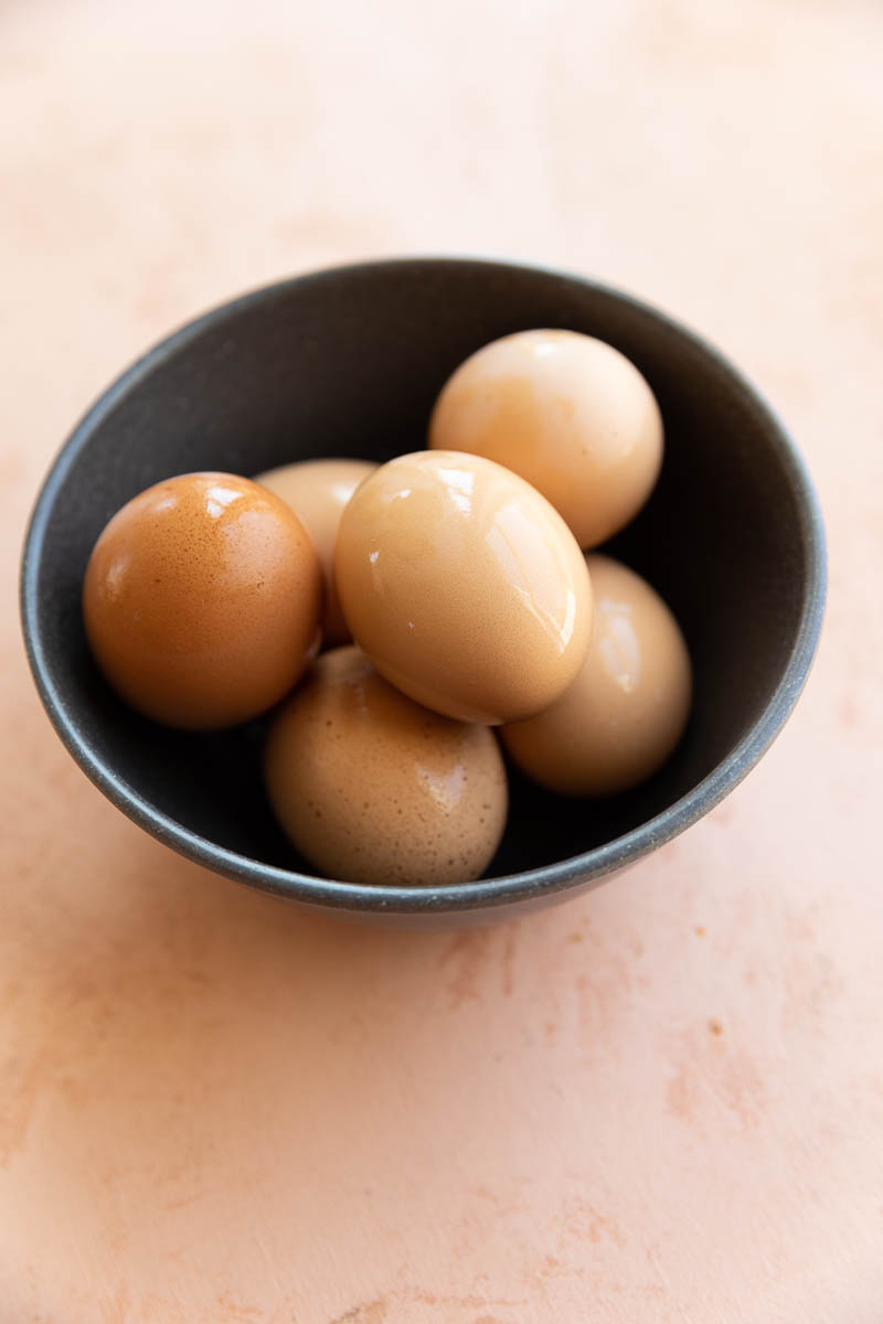 Hard boiled eggs with shells on in a bowl.