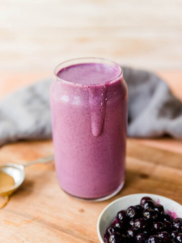 Blueberry protein shake with smoothie dripping down the side.