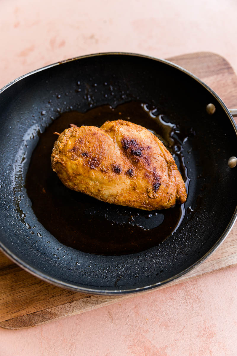 Cooked piece of chicken in a skillet.