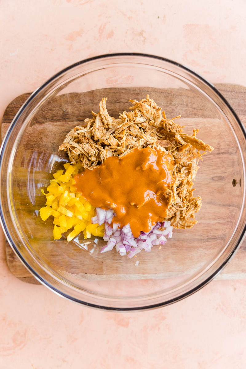 Shredded chicken with buffalo sauce and vegetables in a glass bowl..