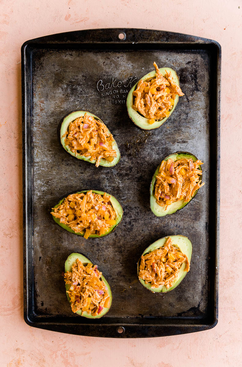 Avocados stuffed on a baking tray.