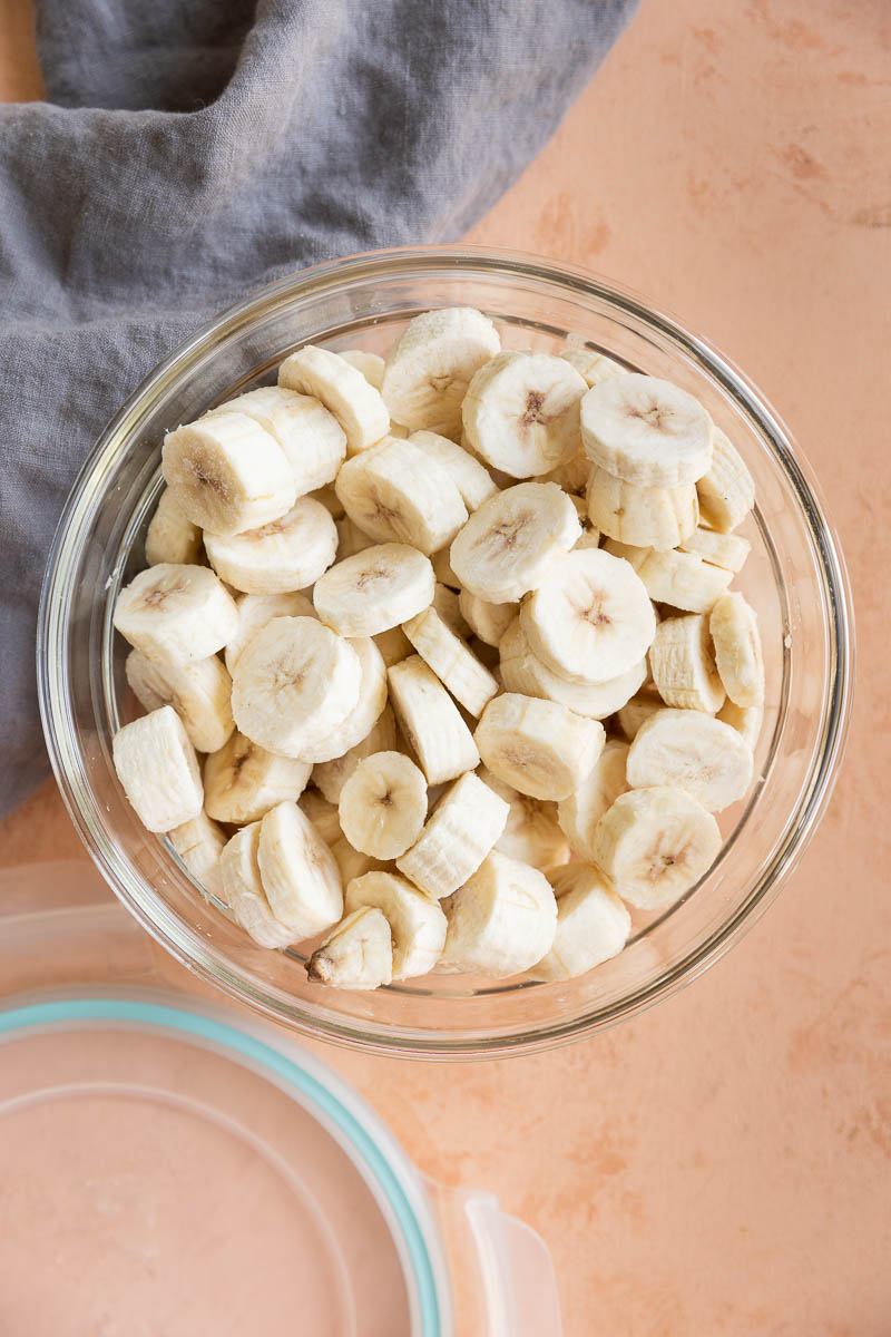 Frozen banana discs in a glass tupperware container.