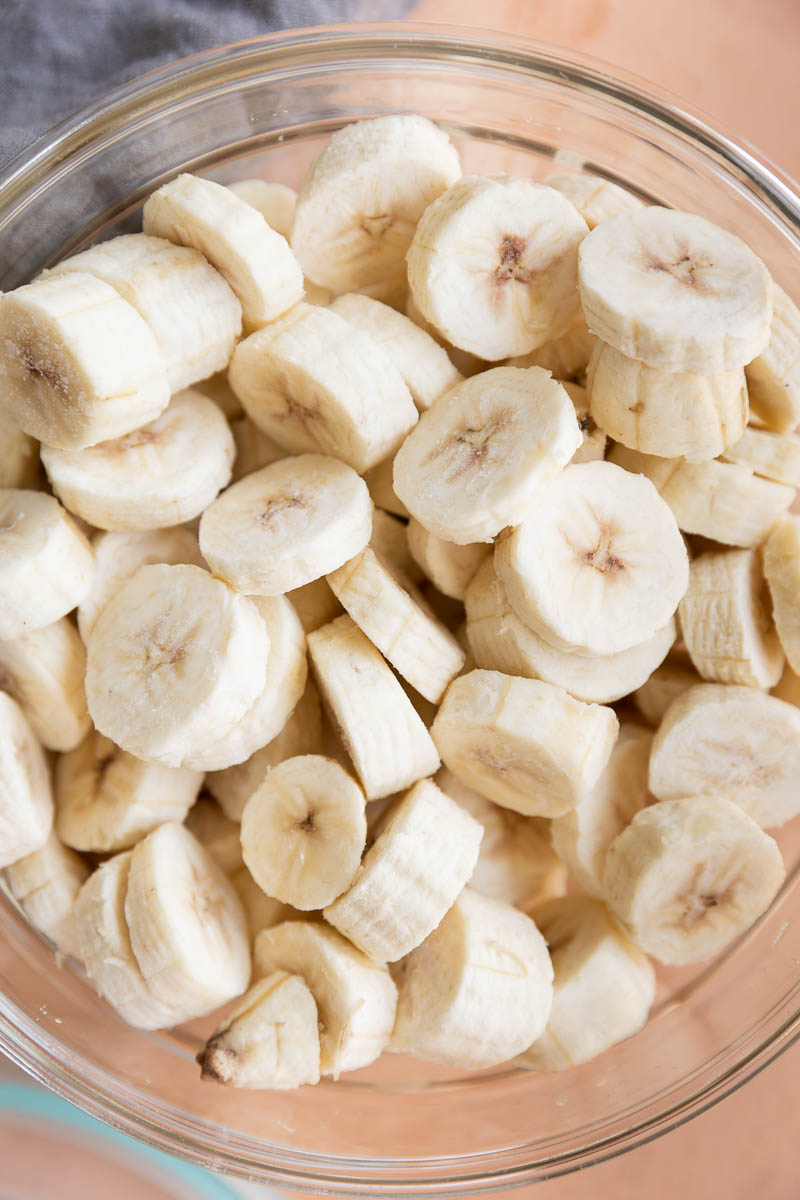 Frozen green banana pieces in a glass container.