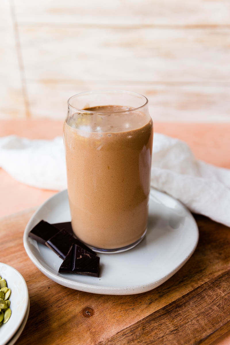 Chocolate banana protein shake in a clear glass cup.
