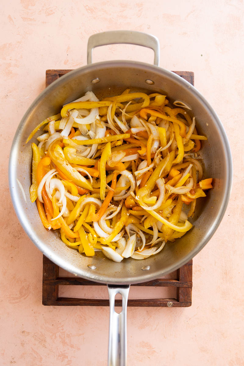 Onions and peppers cooking in a skillet.