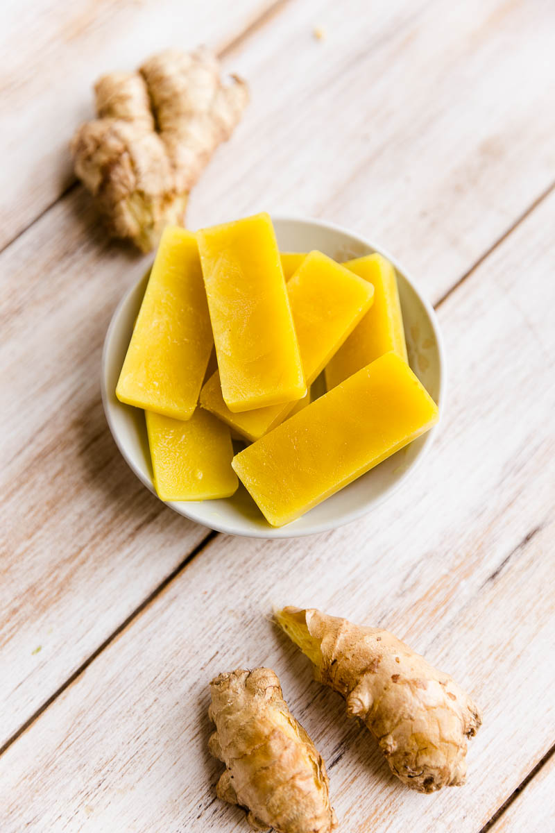 Frozen ginger ice cubes with whole ginger root on the side.